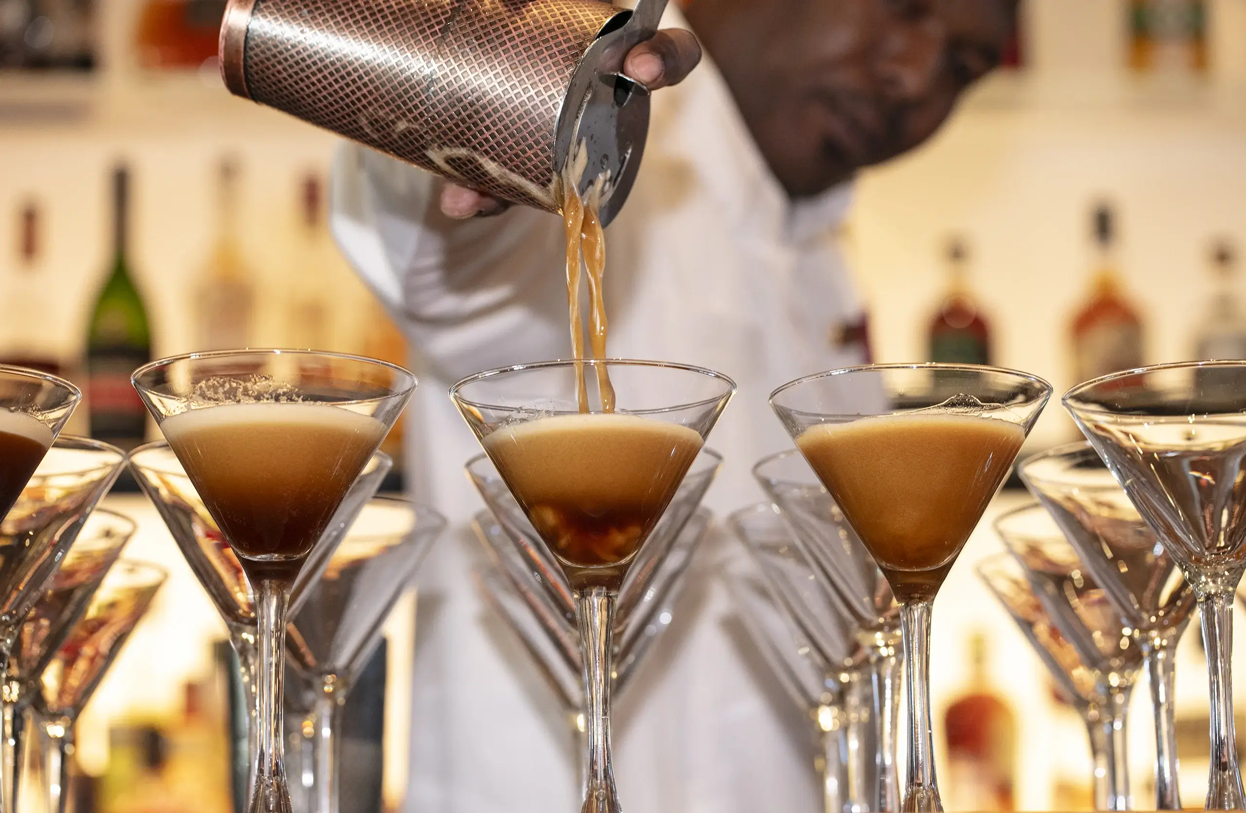 A man pouring cocktails into 3 martini glasses