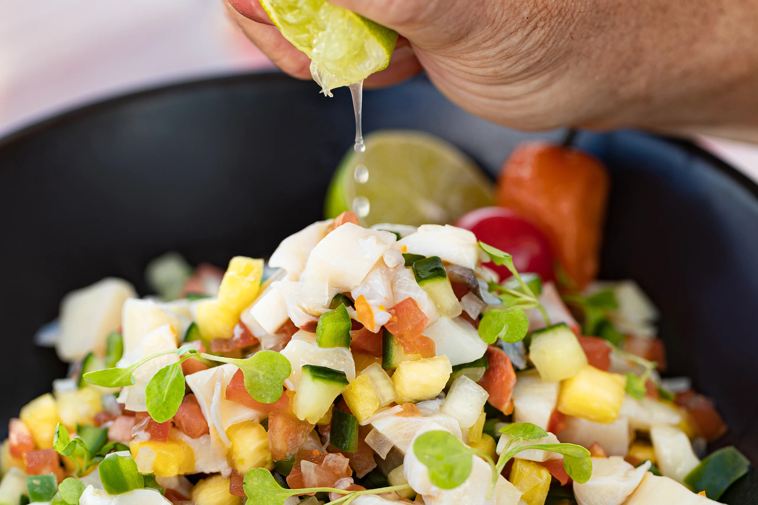 A lime being squeezed over a bowl of Bahamian conch salad