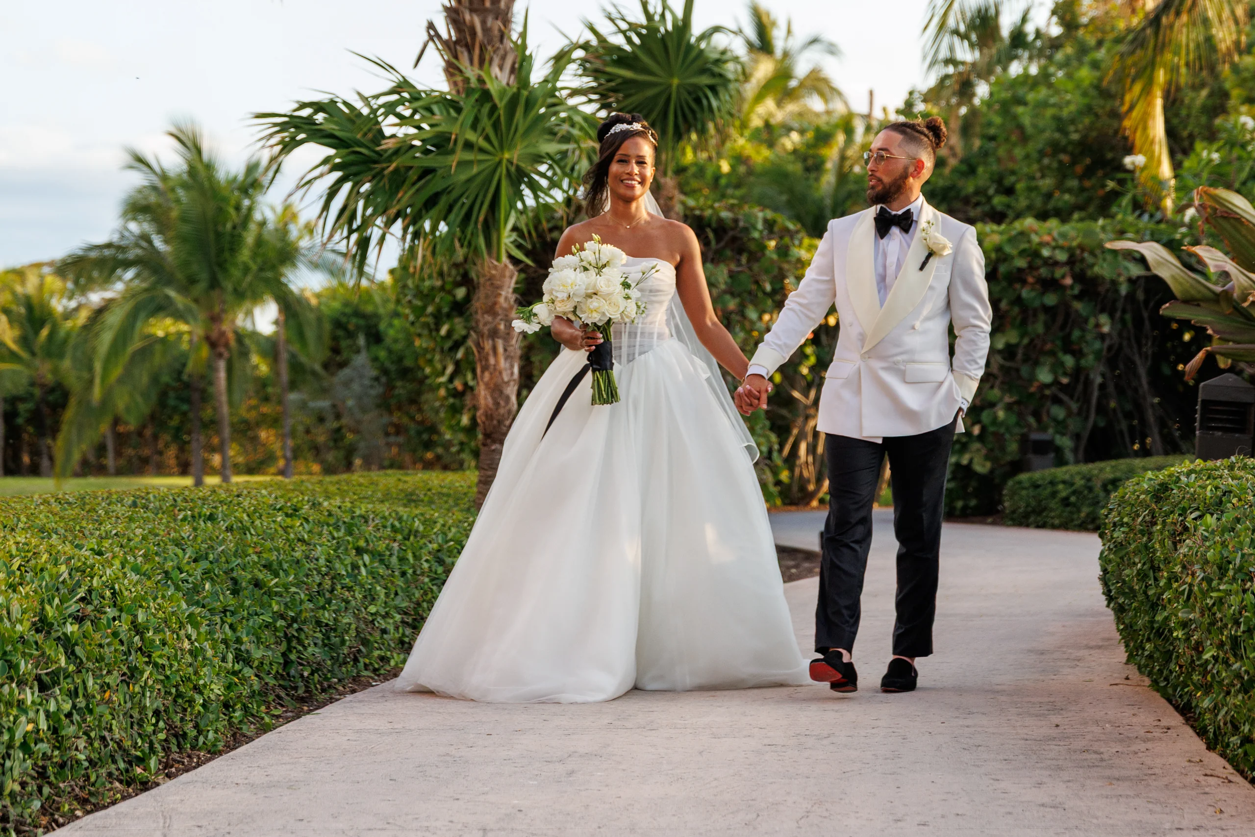 A bride and groom walking a palm-lined path at Atlantis Paradise Island